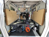 Interior of an RV rental: folded beds, under-bunk storage with gear, and a compact rear kitchen/control console.