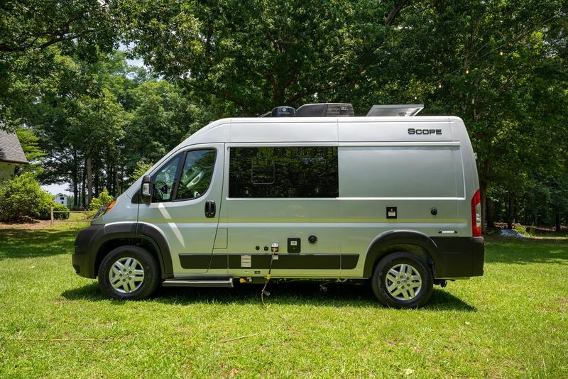 Silver Scope camper van RV rental on green grass, surrounded by trees. Ideal for your next outdoor adventure. — photo 4