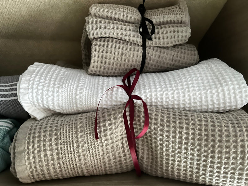 Neatly folded white and beige waffle-weave towels, tied with ribbons, ready for your comfortable RV rental trip. — photo 7