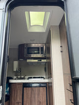 RV rental kitchen: compact galley with microwave, sink, stovetop, and refrigerator. Ideal for road trip cooking & camping.