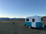 Discover adventure! This RV rental offers vast mountain views, a classic camper, dog, and fire pit under open skies.