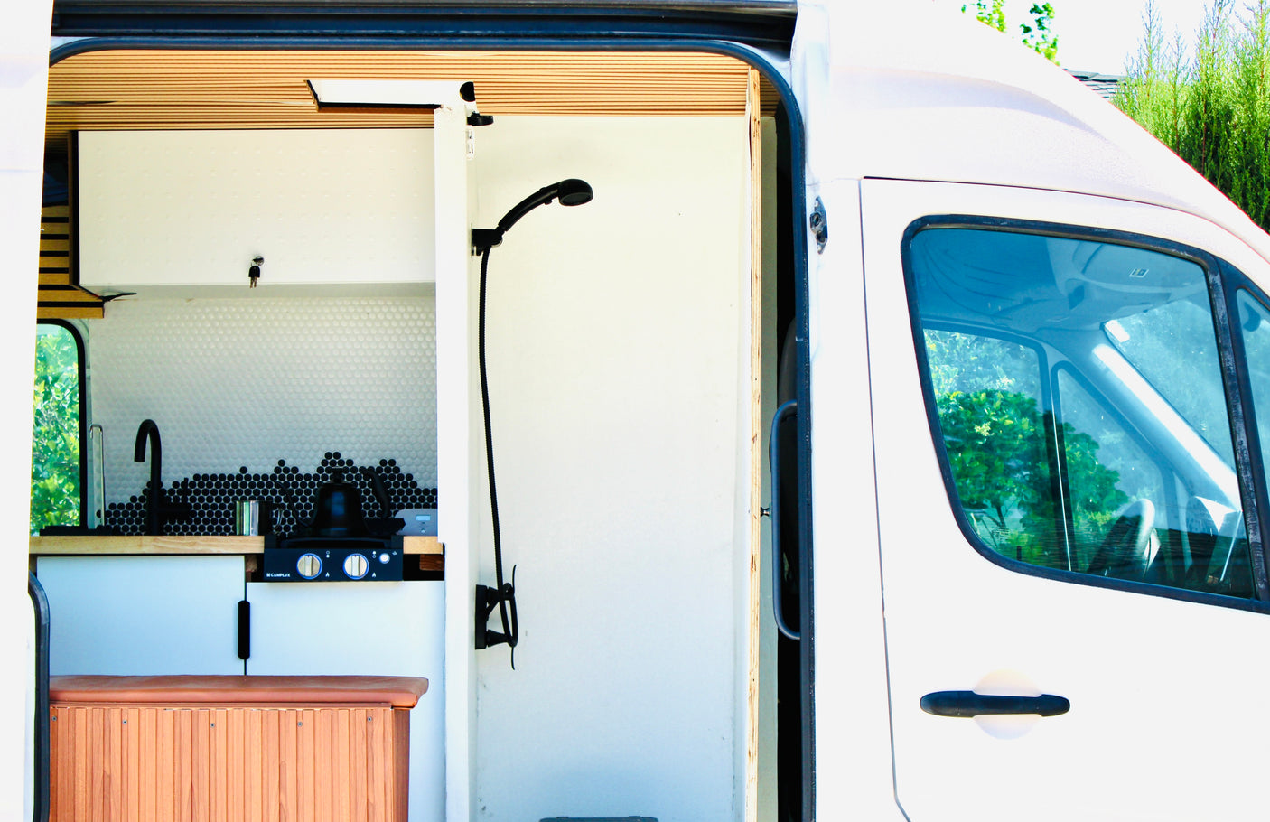 This RV rental features a modern campervan kitchen with a sink, stovetop, and a compact shower, ideal for mobile living.