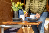 Enjoying comfort in an **rv rental**: a person sets a table with bowls, mugs, and fresh tulips in a wooden camper interior.