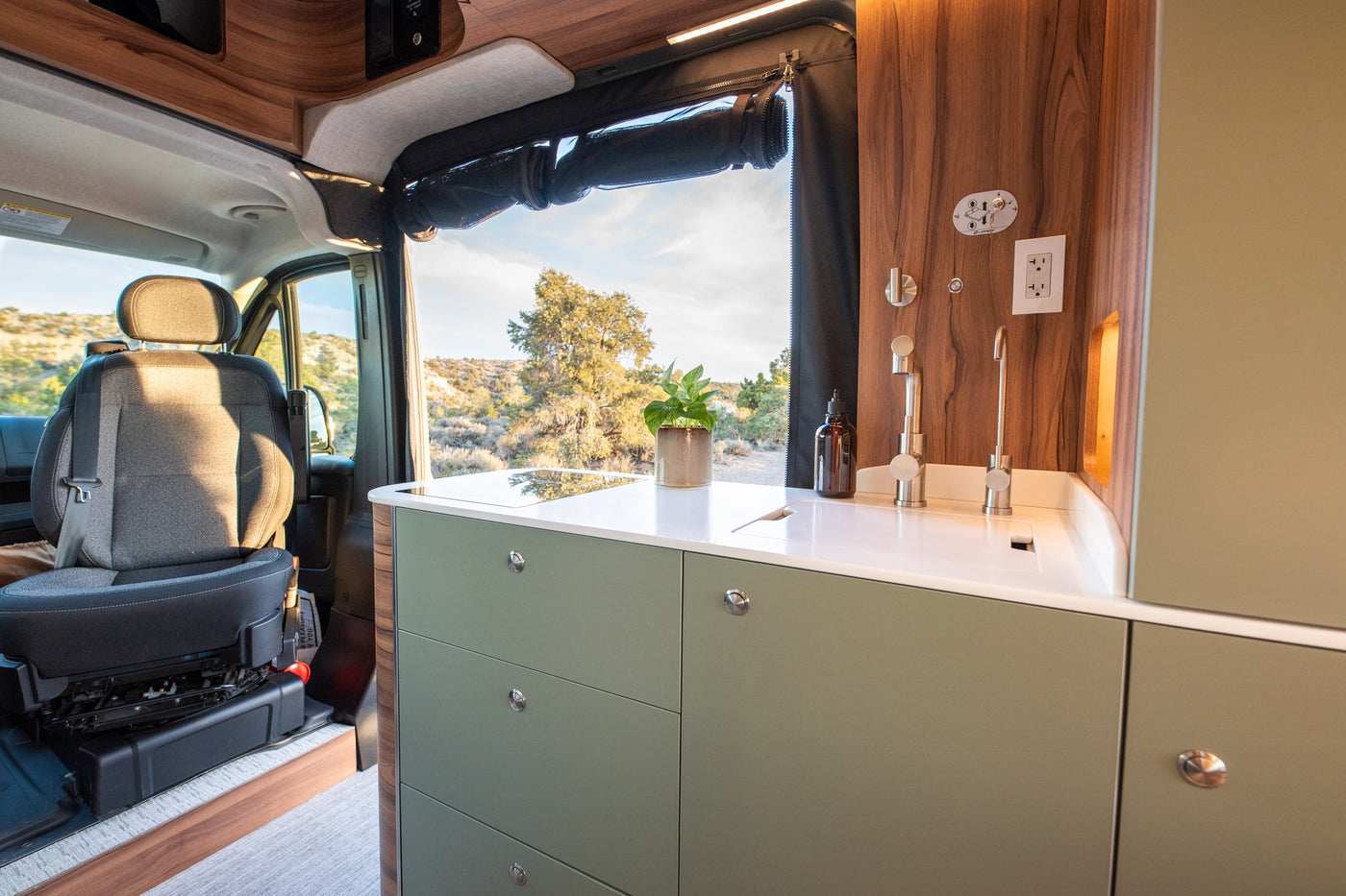 Stylish rv rental interior with a sage green kitchenette, wood accents, and a scenic outdoor view, perfect for road trips. — photo 12