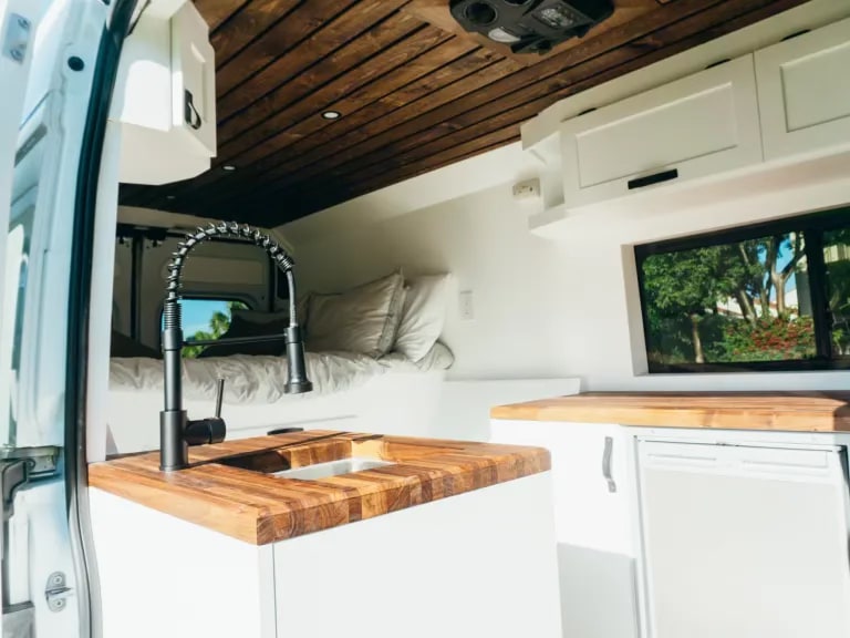  and functional compact kitchen.|A white "Coastal Van Co." RV rental van — photo 3