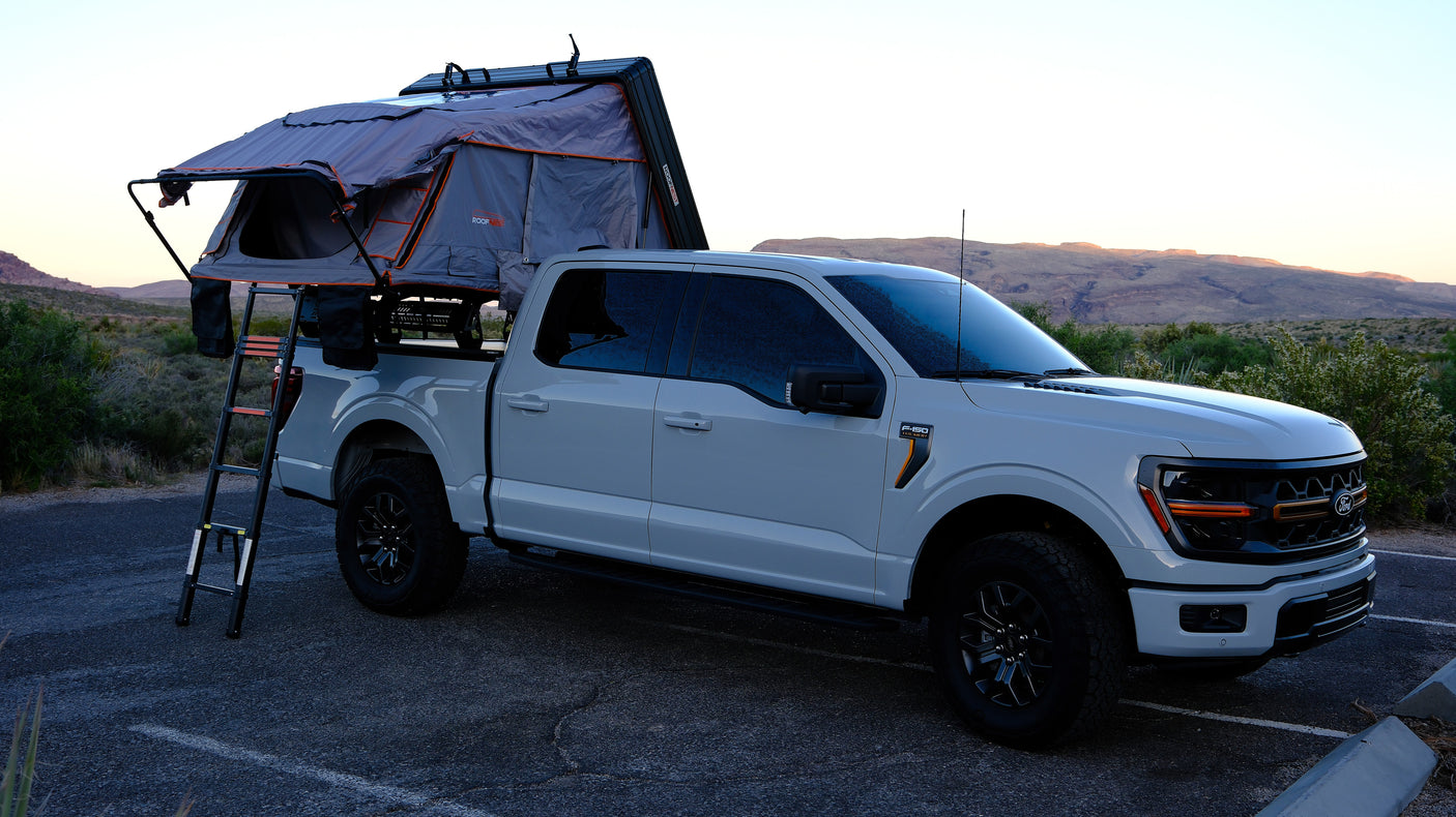 Light grey Ford F-150 pickup with a Roofnest rooftop tent, perfect for an rv rental overlanding trip in a scenic desert.