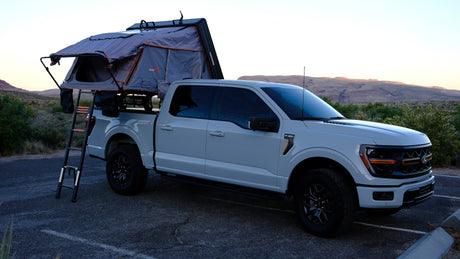 Light grey Ford F-150 pickup with a Roofnest rooftop tent, perfect for an rv rental overlanding trip in a scenic desert.