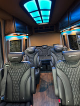 Experience a luxurious rv rental interior: black quilted leather seats, ambient lighting, and a striking blue illuminated ceiling.