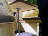 Inside an RV rental: a wooden table, cushioned benches with decorative pillows, with trees visible outside.