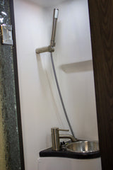 This RV rental's compact bathroom features a versatile shower head, small stainless steel sink, and modern faucet.