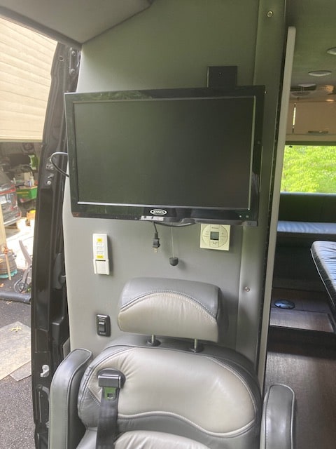 RV rental interior: a mounted flat-screen TV, integrated controls, and a plush captain's chair for travel comfort. — photo 17