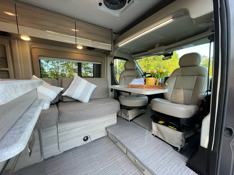 Inside a comfortable RV rental: modern living space with sofa, adjustable table, and swiveling front seats. — photo 9