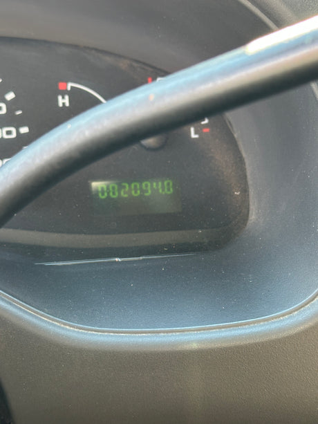 Odometer of an rv rental shows 002094.0, indicating very low mileage. View of dashboard behind a steering column.