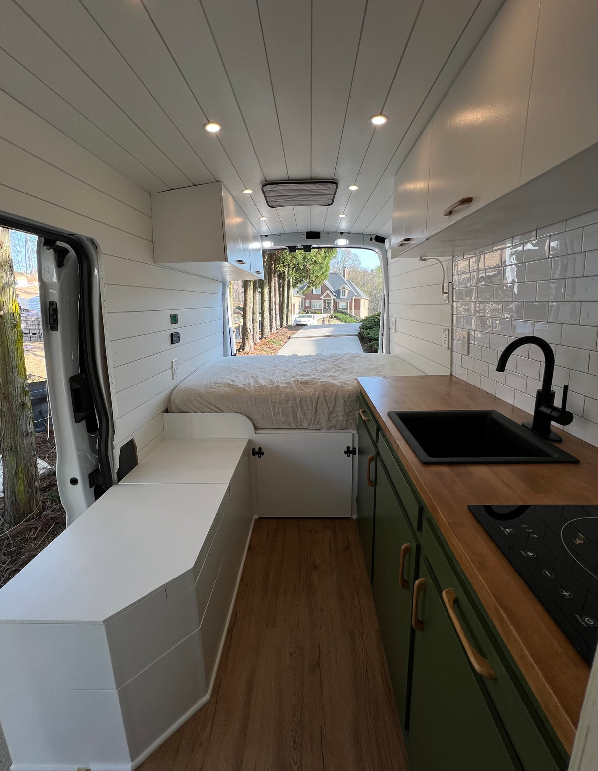 Spacious rv rental interior featuring a comfy bed, green kitchen, and sleek white shiplap walls. Ideal for mobile living. — photo 7