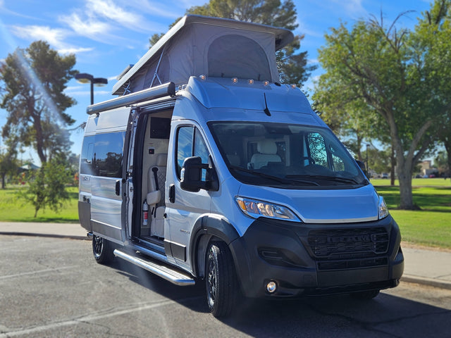 Sleek silver pop-top RV rental, side door open. This modern camper van is ready for your next adventure!
