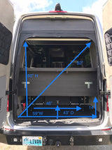View of an RV rental's rear interior showing the custom bed platform and storage: 14" high cargo area, 82" diagonal bed.