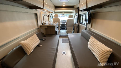 Inside this rv rental: Compact kitchen, twin benches for seating/beds, and front cockpit view.