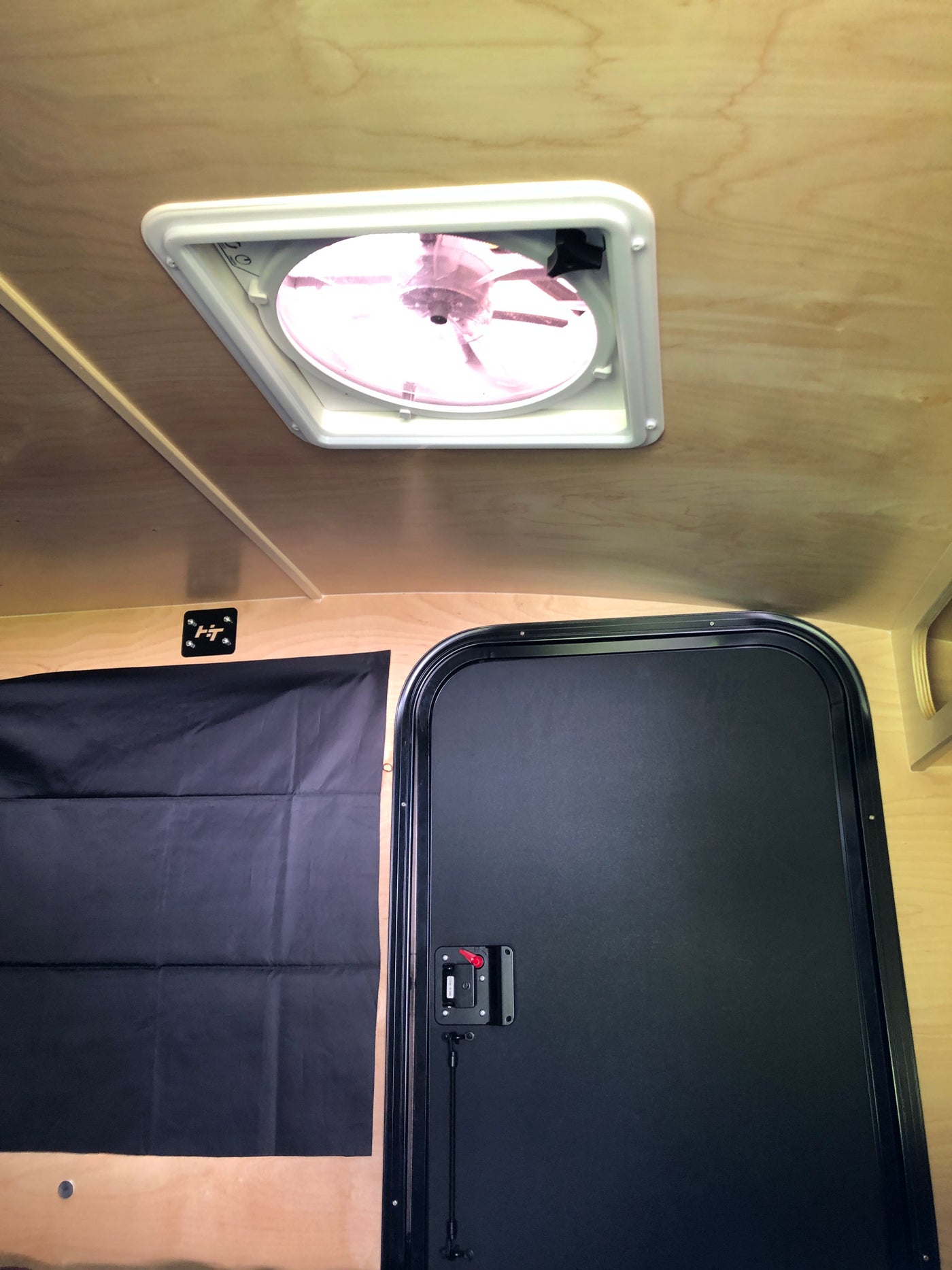 Inside an rv rental: light wood interior with a ceiling fan, black privacy curtain, and door, ready for your next adventure. — photo 7