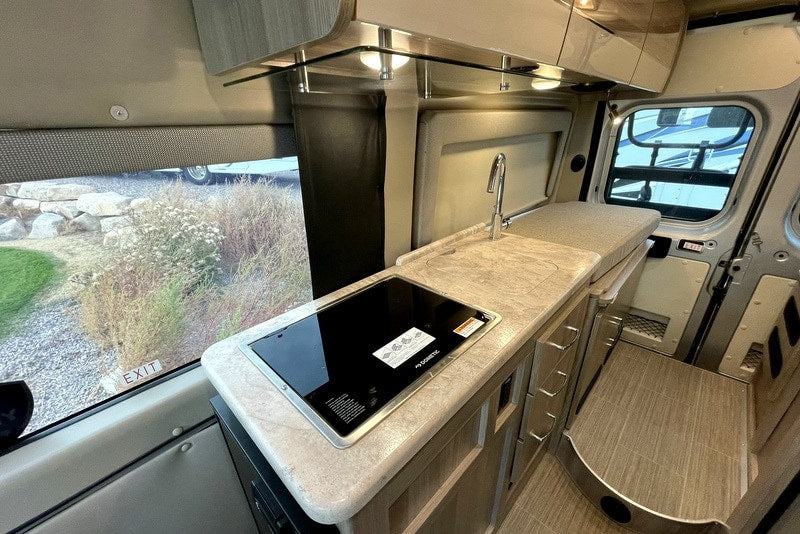  revealing cloudy skies above the fabric walls.|Inside an RV rental: a plush pop-top bed with mesh windows. Perfect camper sleeping area for comfortable travel adventures.|Cozy RV rental interior shows overhead storage with open compartments — photo 8