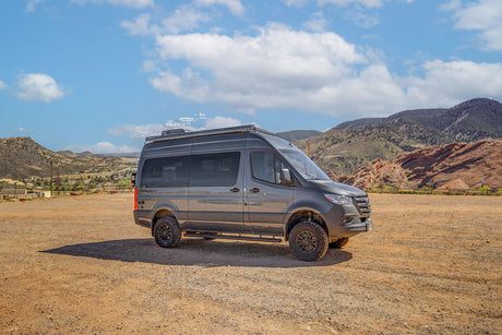 Explore scenic routes with this rugged gray Mercedes-Benz Sprinter RV rental, perfect for mountain road trips and adventure.