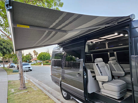 Luxury RV rental van with an extended awning, bright LED lights, and a premium, well-appointed interior.