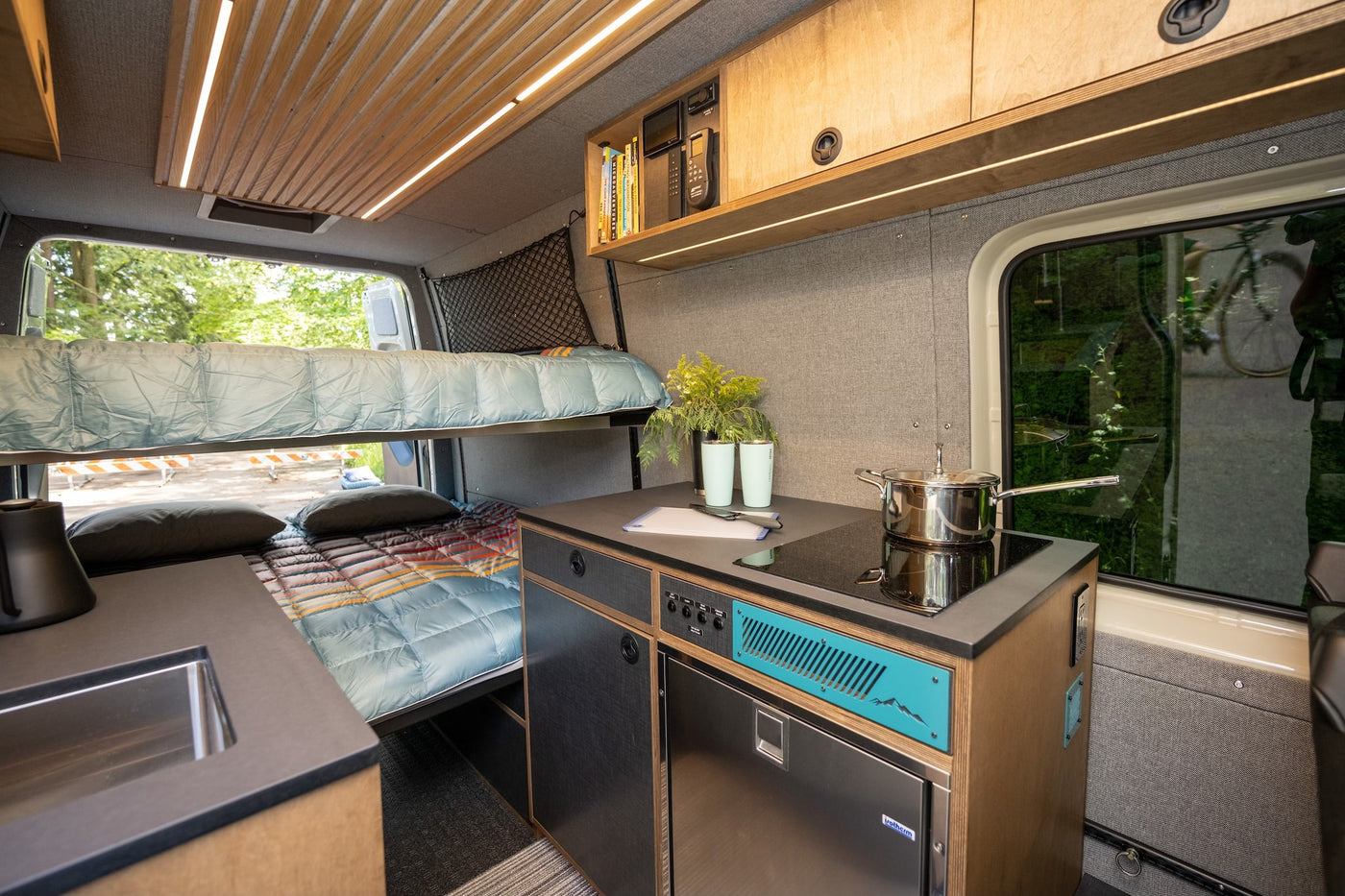 This modern RV rental showcases a versatile camper van interior with a well-equipped kitchen and cozy bunk beds. — photo 8