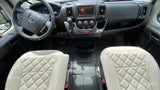 RV rental cockpit view: light quilted seats, steering wheel, and dashboard with display and controls. Ideal for your next adventure.