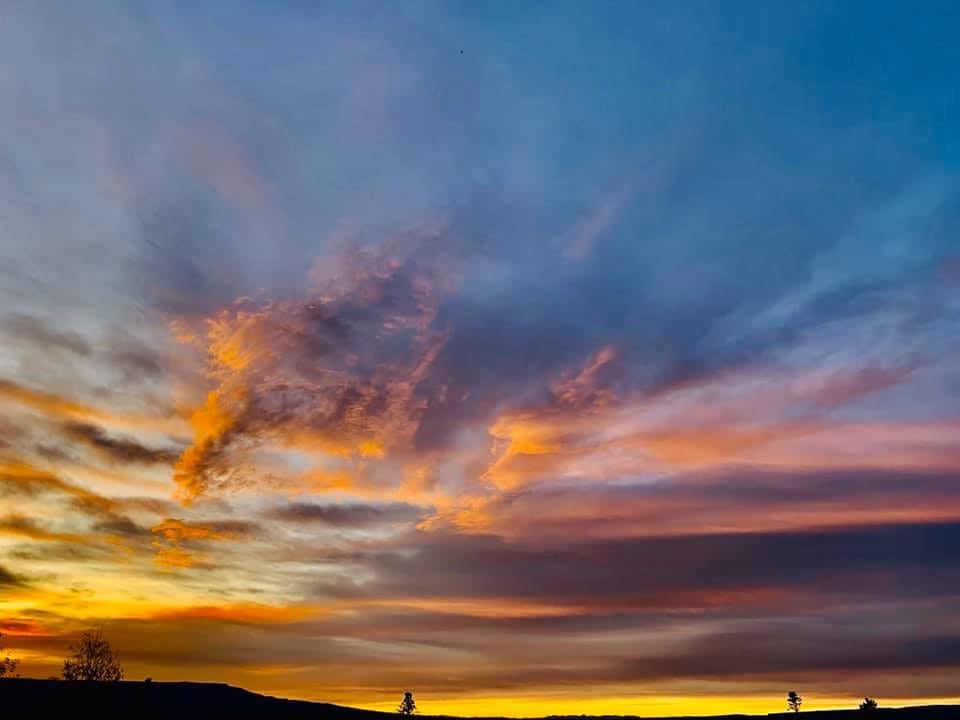 Vivid sunset sky, orange, pink, blue, over dark hills. Imagine this view from an RV rental! Perfect for outdoor adventures.