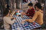 Friends and family enjoy games like Jenga and cards at an RV rental campsite picnic table.