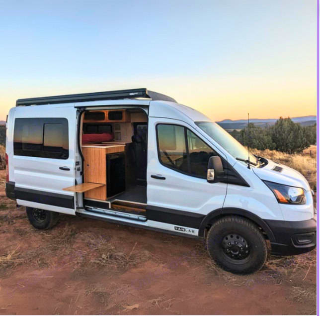 Adventure-ready white off-road RV rental camper van. Open door reveals wood interior & bed for your next van life adventure.|Inside a modern RV rental: well-equipped kitchen
