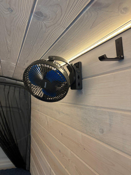 RV rental interior: A clip-on fan (Koonie) and hook on paneled walls, with LED lighting and mesh netting for comfort.