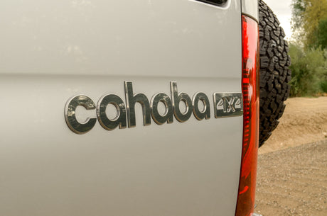Rear view of a Cahaba 4x4 RV rental, highlighting its rugged tire, red taillight, and distinctive emblem.