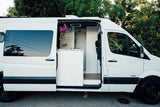 White camper van, ideal for rv rental, showing its custom interior with compact kitchen, shower, and decor.