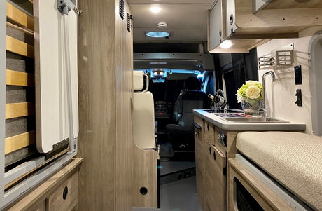 Compact RV rental interior featuring a functional kitchen, convertible bed, and comfortable living space. Perfect for travel.