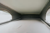Inside a spacious pop-top RV rental with a comfortable raised bed, showing the tent walls and clear windows.