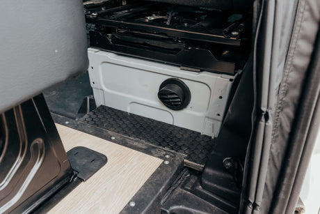 RV rental: Camper van interior with passenger swivel seat base, circular air vent, and custom flooring.