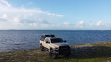 Tan Ram Power Wagon overland build with rooftop tent on the coast. Consider this rugged rv rental for your next trip.