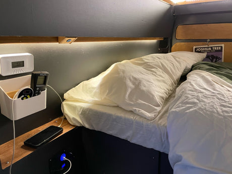 Experience comfort in this RV rental! Features a cozy bed, ambient lighting, phone charging station, and thoughtful organization.