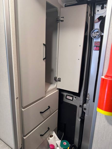 This RV rental's organized interior features an open cabinet, drawers, and compact storage for road trip essentials.