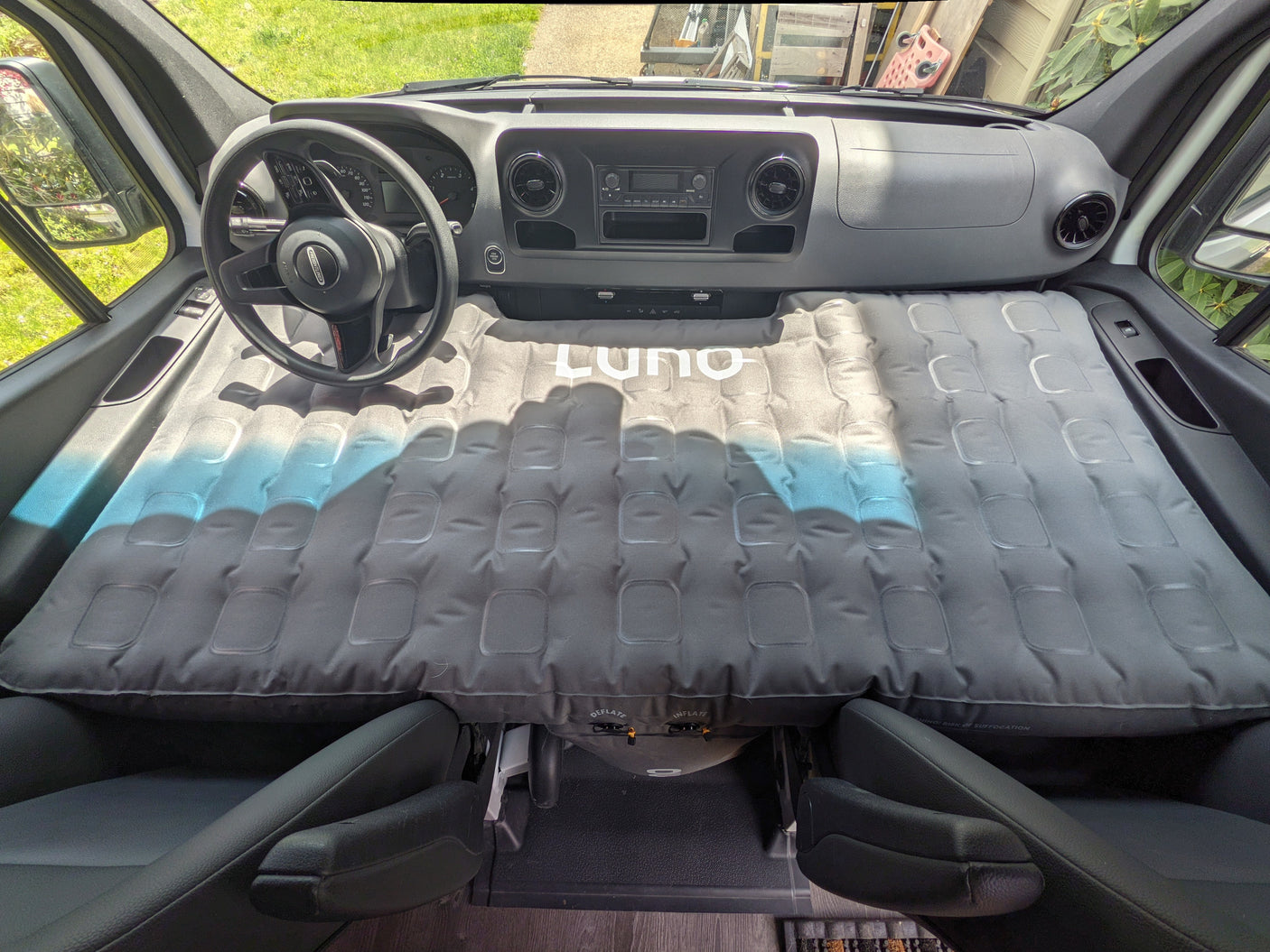RV rental van's front cabin transformed into a sleeping space with a gray Luno air mattress, perfect for a camper road trip.
