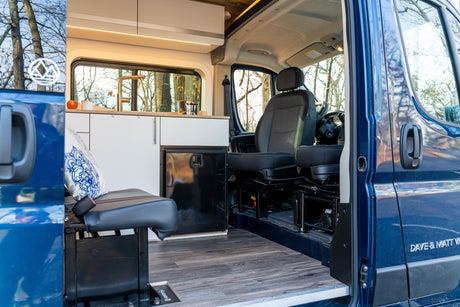 Spacious rv rental camper van interior. Features compact kitchen, bench seat, and front cabin area with driver's seat.