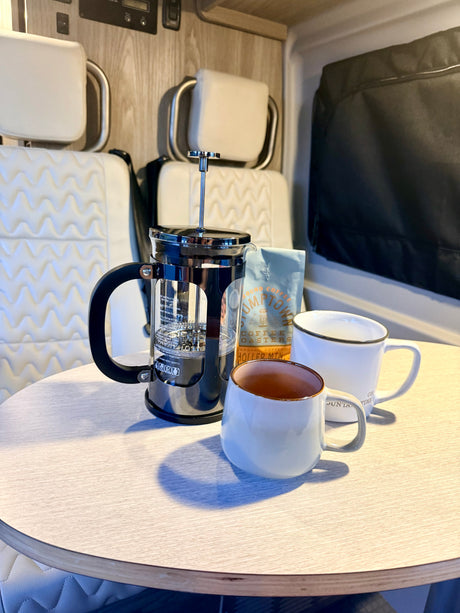 Morning coffee in an RV rental: French press, Stumptown coffee, and two mugs on a table, with comfortable seating.