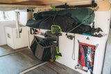 RV rental storage: Organized camper cargo holds a shovel, Gerber tool, gear bags, coiled hoses, and a first aid kit.