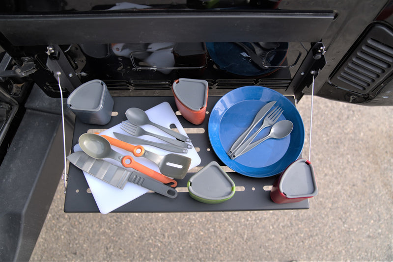 This RV rental camping kitchen, complete with plates, utensils, and a cutting board, is neatly arranged on a fold-down table. — photo 6
