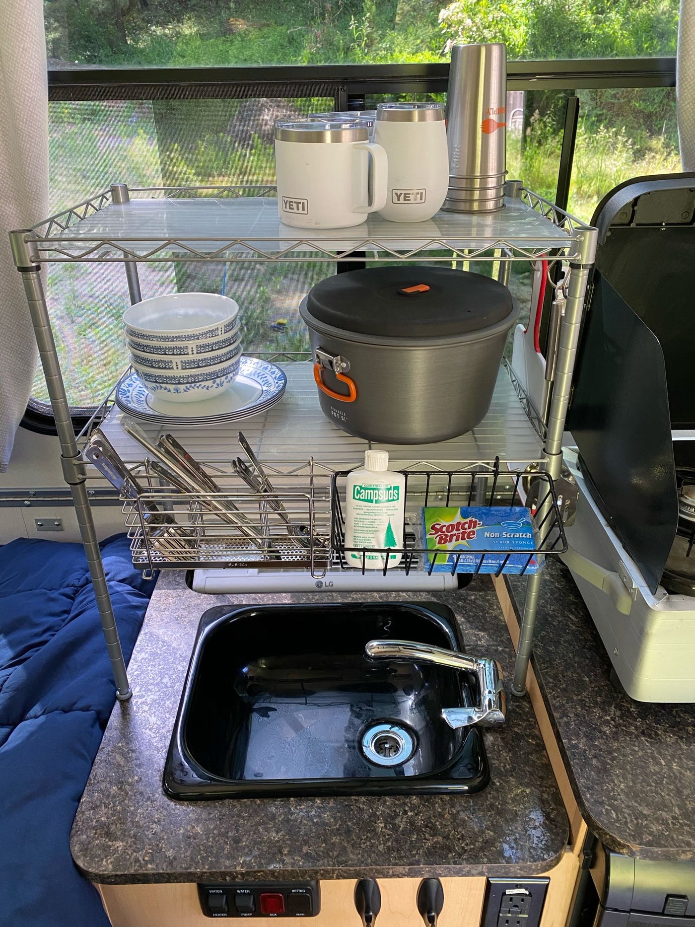  large window view of vibrant green nature.|Cozy A-frame rv rental interior showcasing a bed — photo 2