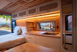 Cozy rv rental interior with a fully equipped kitchen, comfortable bed, and a stunning scenic view out the window.