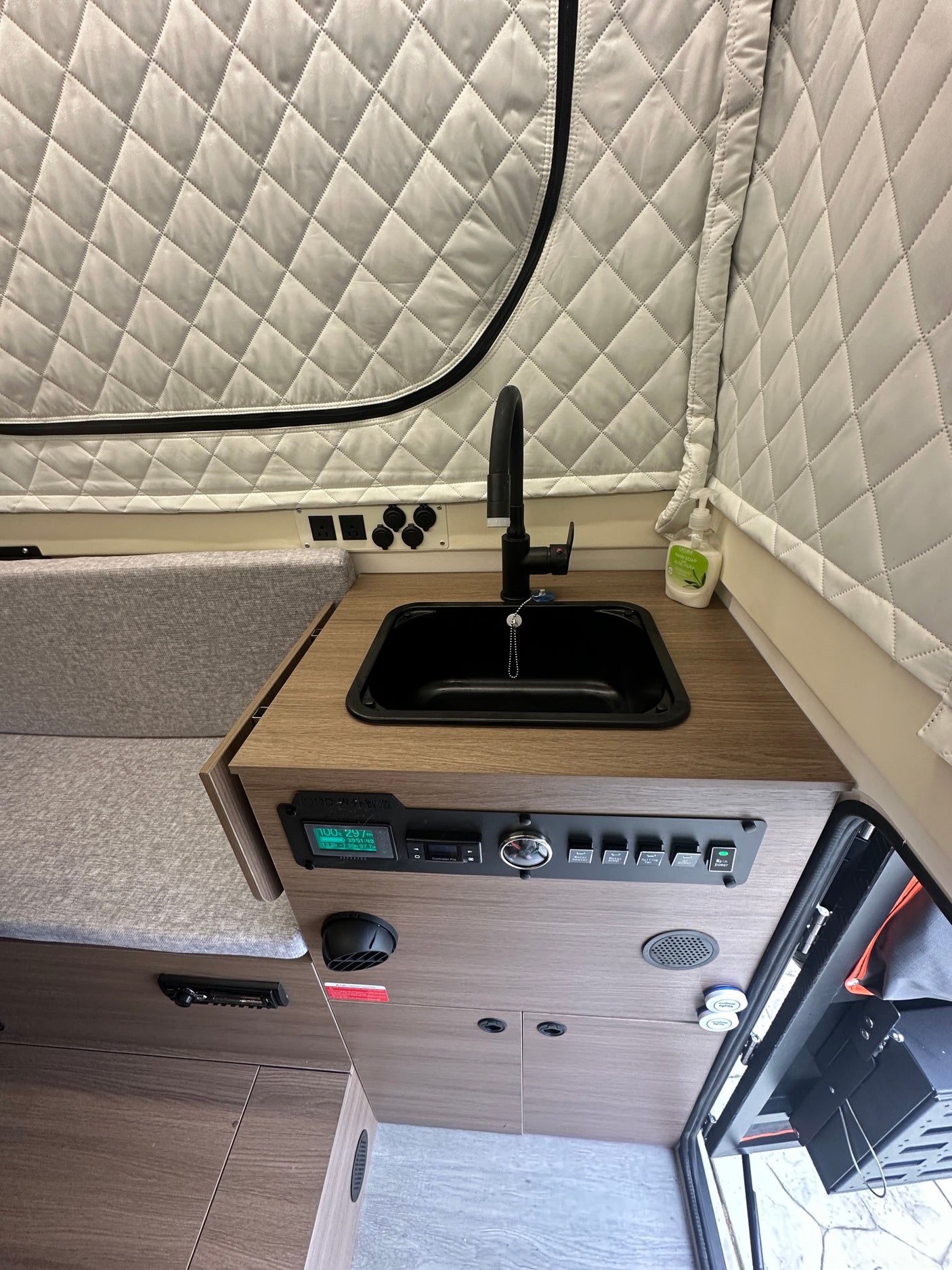 RV rental interior: compact kitchenette with sink, faucet, and power control panel, ideal for mobile living.