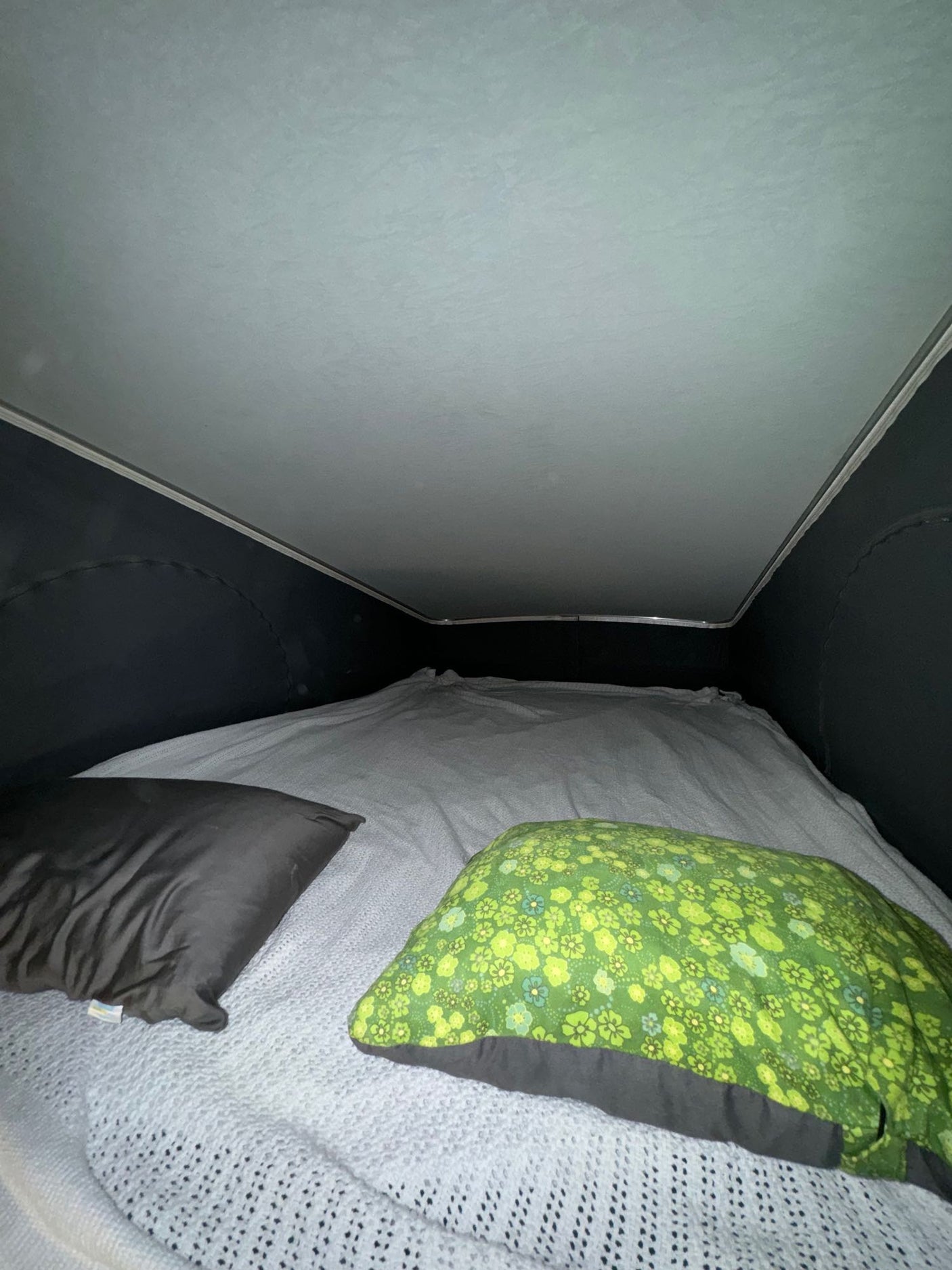 Inside a pop-top RV rental: a cozy bed with white bedding and two pillows, perfect for camper van adventures.