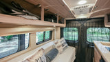 Experience adventure in this RV rental! Interior shows a comfortable seating/sleeping area, storage, and kitchenette.