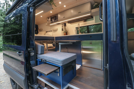 Explore this modern RV rental! Spacious camper van interior with full kitchen, dining area, and cozy bed for your adventures.